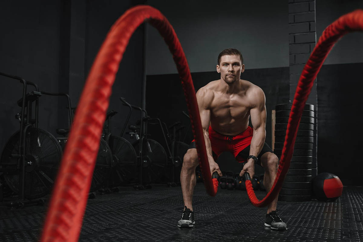 muscular-man-doing-battle-ropes-exercise-crossfit-gym